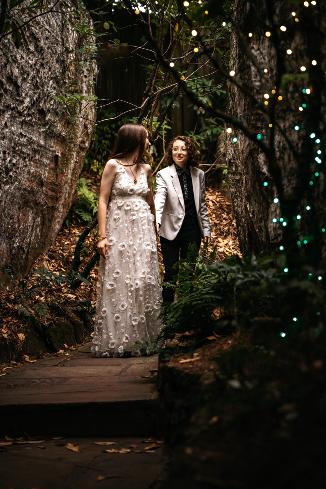 Two brides on a lantern-lit forest path