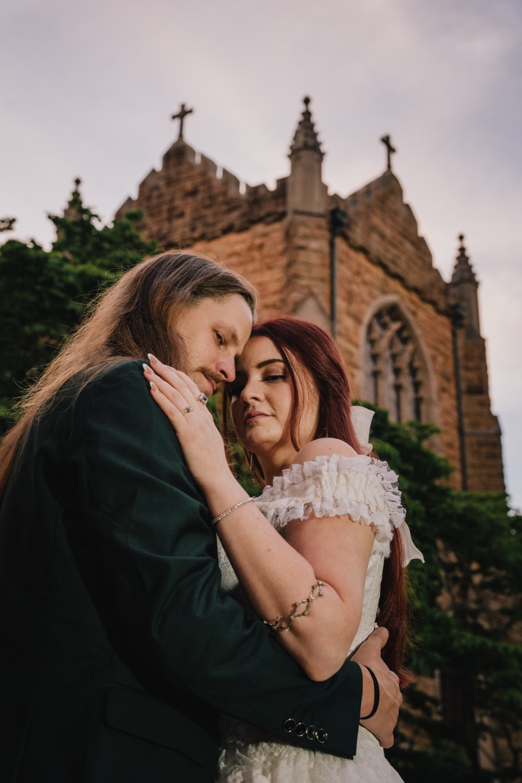 Couple embracing at dusk in front of a gothic stone church